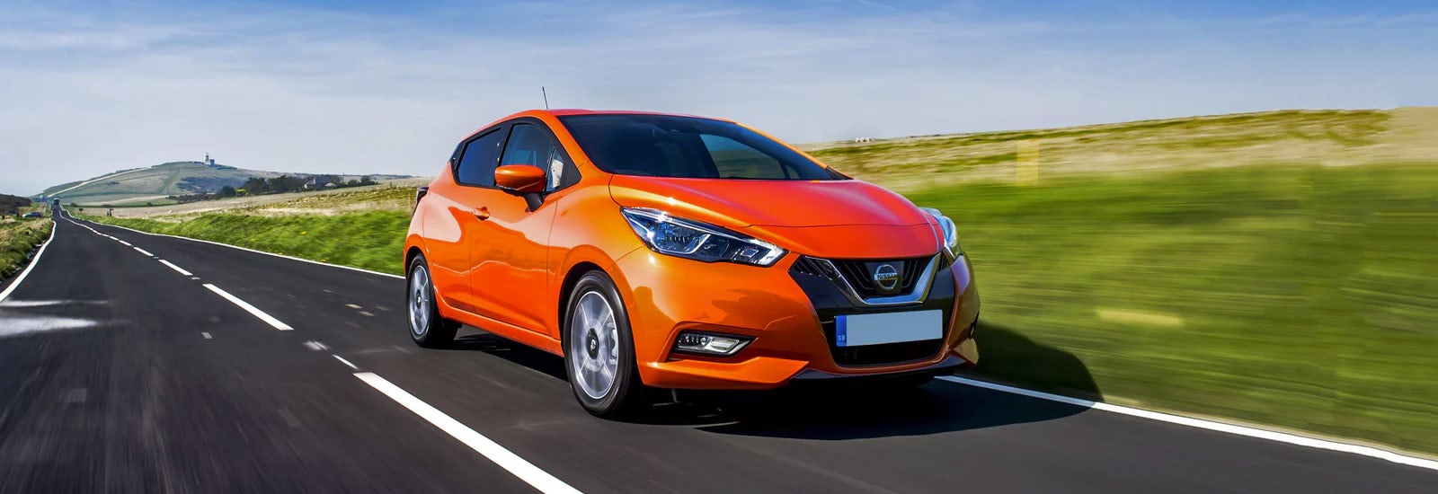 Orange Nissan Micra driving, viewed from the front